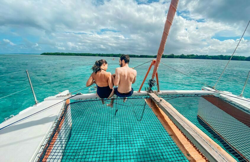 couple assis de dos sur le devant du catamaran