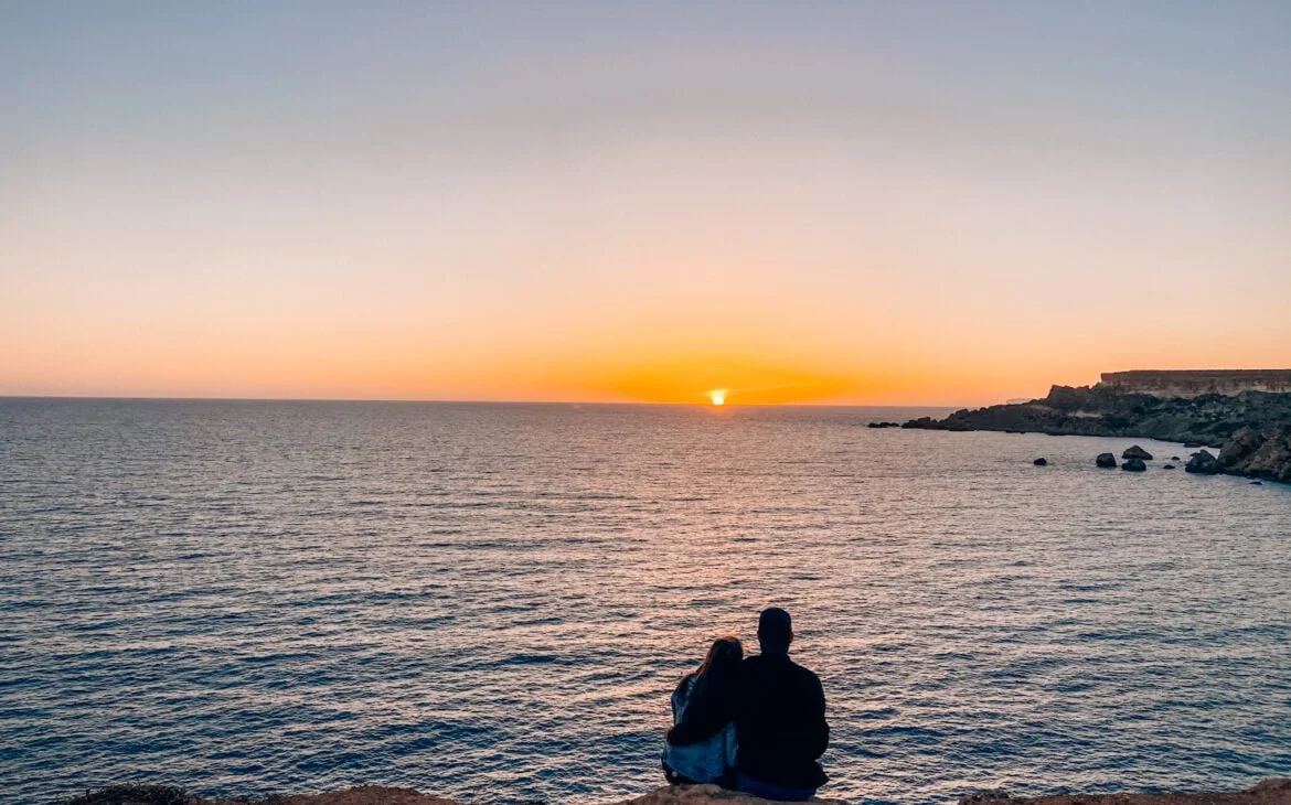 Couple assis devant un coucher de soleil à Golden Bay